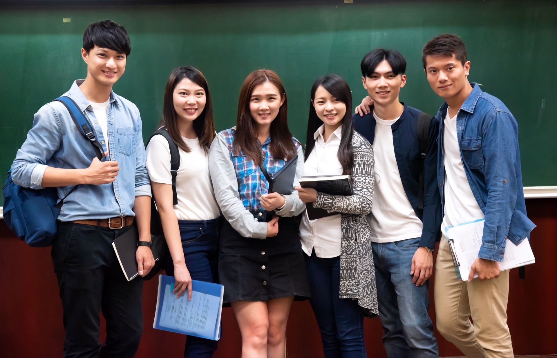 Group of university students standing proud in front the auditorium stage