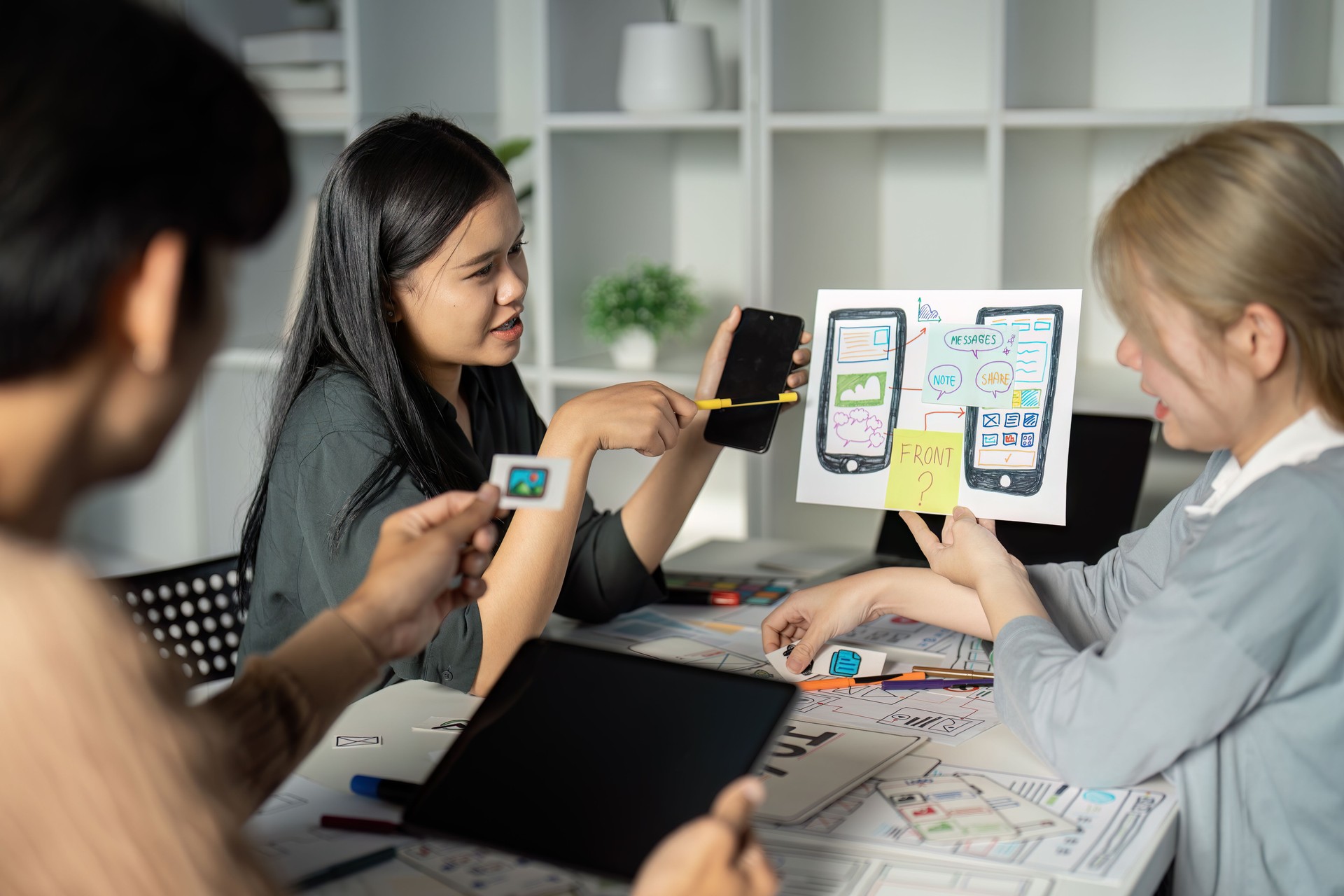 Creative UX/UI Design Team Brainstorming Session with Digital Devices and Wireframes in Modern Office Environment